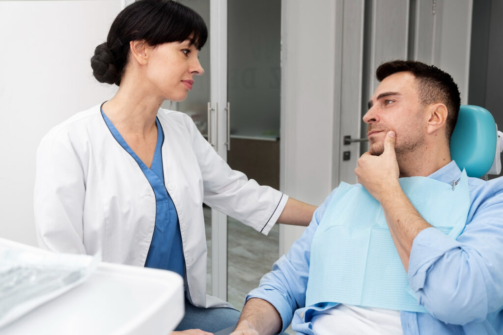 Speech therapist speaking with an adult man in a clinic, discussing symptoms during an oral or swallowing evaluation.